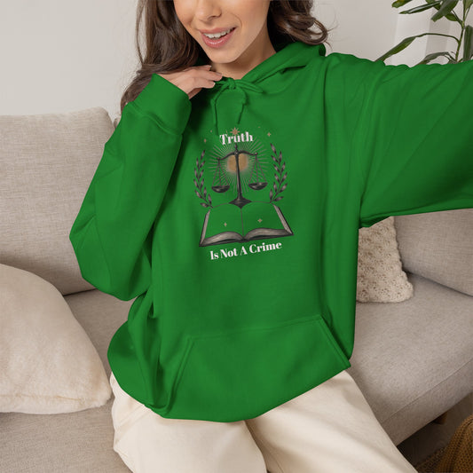 A woman wearing a bright Irish green pullover hoodie with a graphic print on the front. The graphic features a book with a scale of justice and the text 'The Truth Is Not A Crime'.